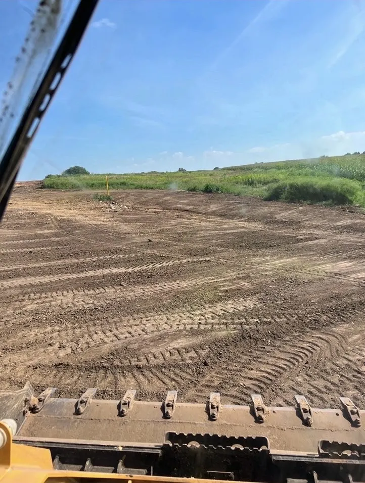 View from the cab of a track loader over a large graded field